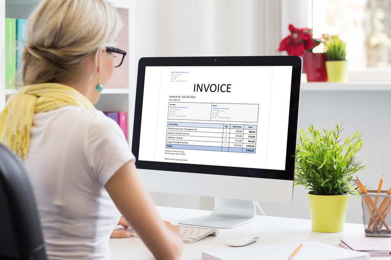 https://www.irisbusiness.com/wp-content/uploads/2024/05/woman-office-with-sample-invoice-document-computer-1.jpg